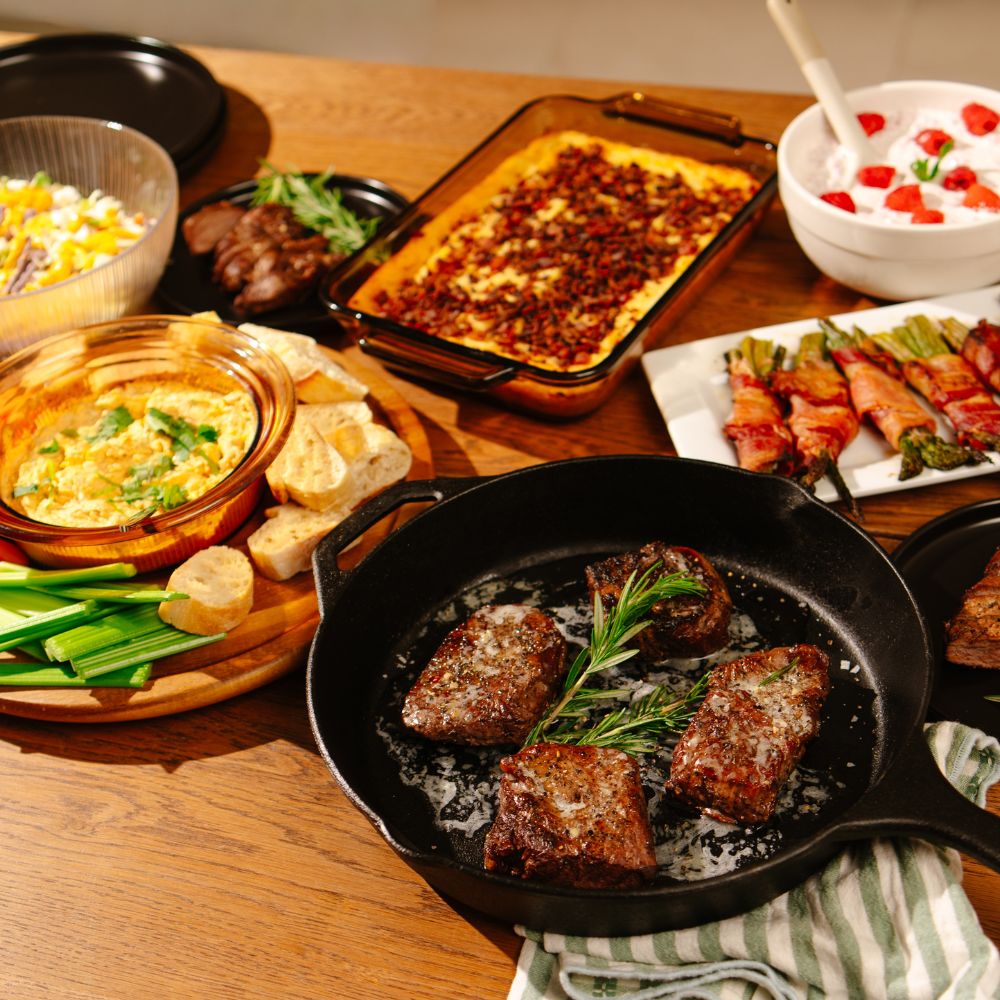 Diverse food items including meat, vegetables, and dips on a wooden table.