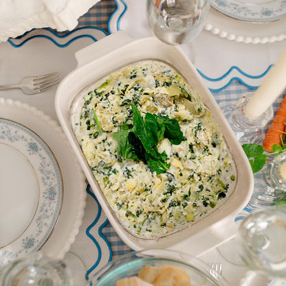Spinach Artichoke dip on a table setting with plates and glasses.