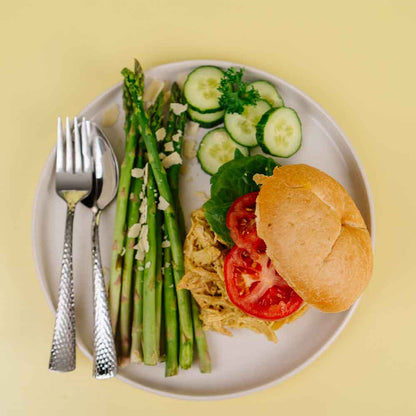 Plate with asparagus, cucumber slices, a sandwich, and vegetables on a yellow background