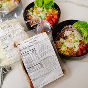 Prepared meal with nutrition label and bowls of salad in the background