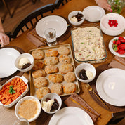 Dinner table set with various dishes including a tray of chicken pillows, a casserole dish, and small bowls of food.