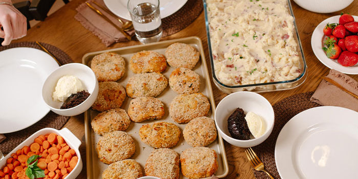 Dinner table set with various dishes including a tray of chicken pillows, a casserole dish, and small bowls of food.