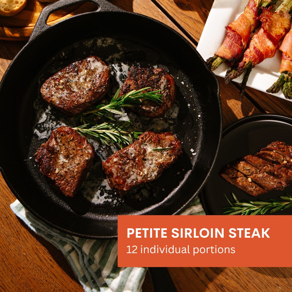 Cast iron skillet with petite sirloin steaks and rosemary, with a plate of wrapped asparagus in the background.