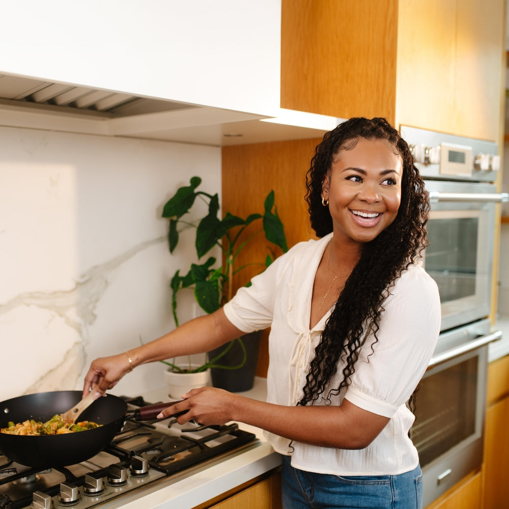 Woman cooking Beehive Meals Flat Top Meals in a kitchen, smiling at the camera
