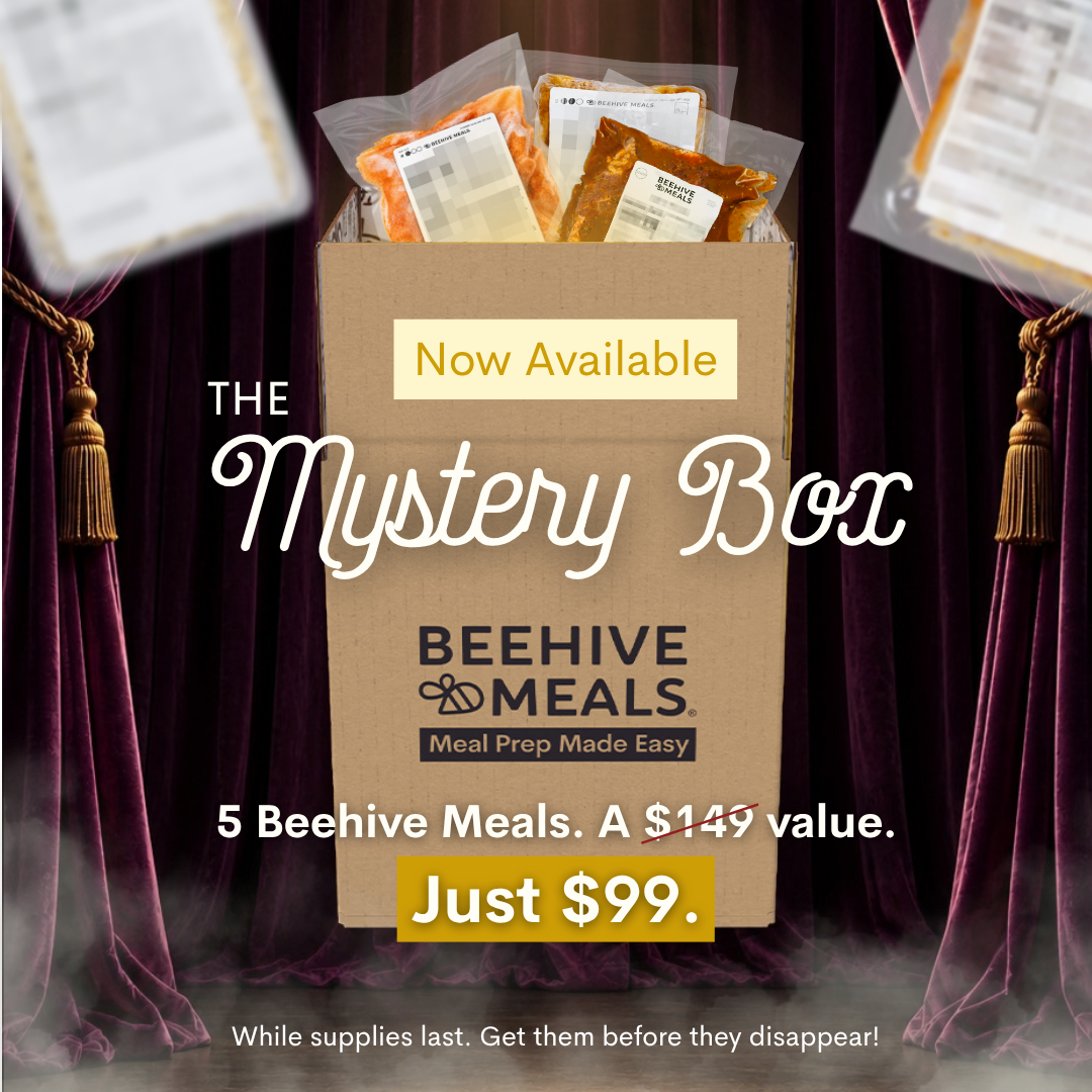 A cardboard box labeled 'BEEHIVE MEALS' with 'Now Available' and 'Just $99.' on a promotional graphic, surrounded by dark purple curtains and floating meal packages.