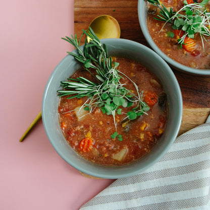 Bowl of soup with garnishes on a pink surface