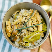 Bowl of shredded chicken with green beans and rice on a blue and white striped towel.