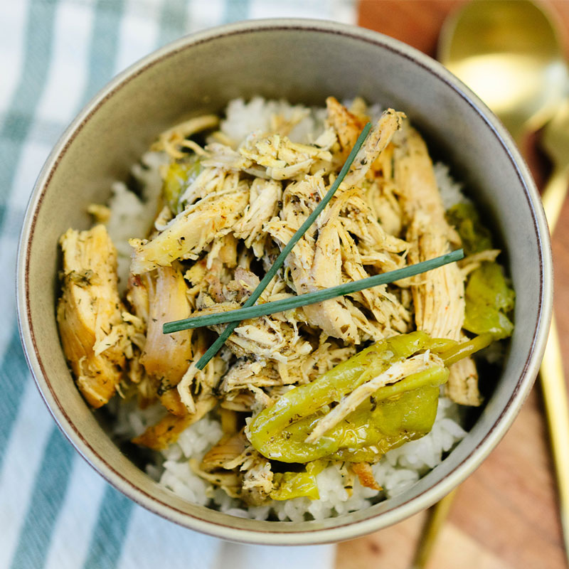 Bowl of shredded chicken with green beans and rice on a blue and white striped towel.