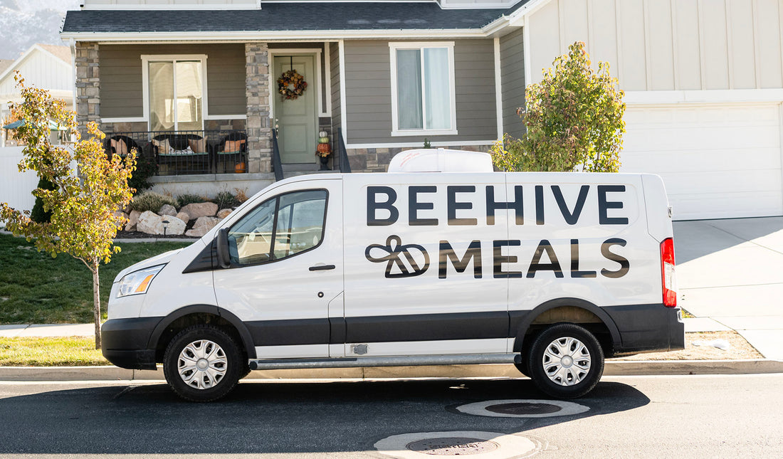 Beehive Meals van parked in from of a grey house.